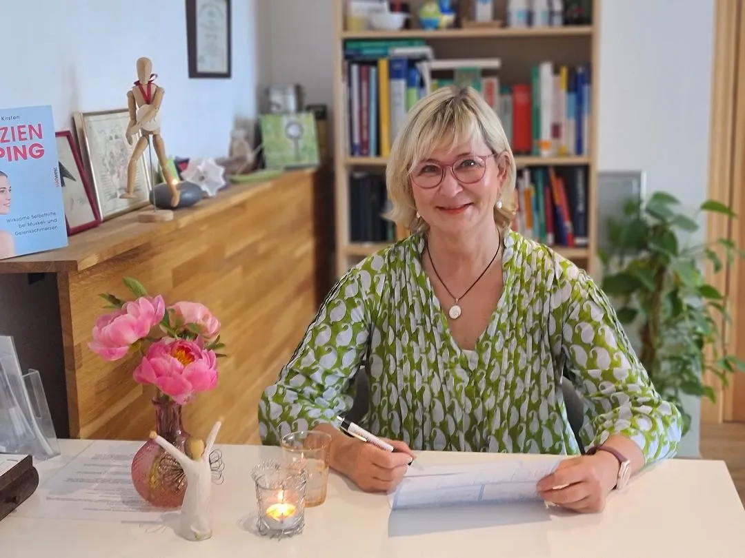 Kerstin Loss in ihrer Praxis an einem Tisch mit Blumen