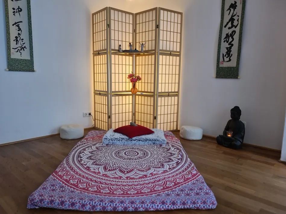 Heller Behandlungsraum mit Liege, Paravent und Buddha-Figur
